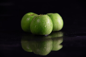 fresh juicy green apples, in drops of dew on a black background
