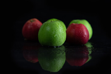 fresh juicy green and red apples, in drops of dew on a black background