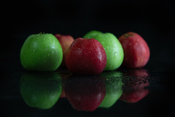fresh juicy green and red apples, in drops of dew on a black background