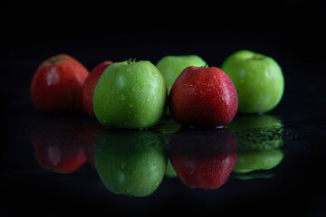 fresh juicy green and red apples, in drops of dew on a black background