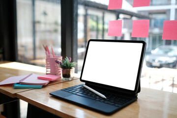 Photo of an empty screen digital tablet with stylus pen surrounded by feminine objects on a wooden...