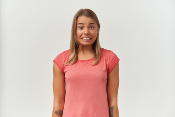 Obraz premium Indoor shot of young adult female, looks into camera and grins, confused facial expression. Isolated over white background