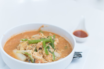 Sukiyaki, in a white cup, sits on the table.