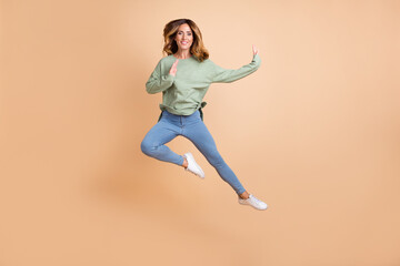 Fototapeta na wymiar Full length body size photo woman jumping high got karate training isolated pastel beige color background