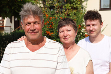 Portrait of Caucasian family of three. Father and mother are 62 year old, senior people. Their son is a 32 year old young man. They looking into camera.