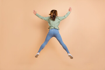 Fototapeta na wymiar Full length body size back view photo woman jumping up in casual clothes isolated pastel beige color background