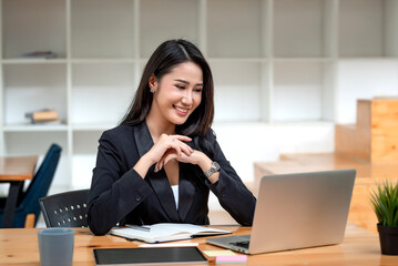 Happy young Asian businesswoman sitting at the office using laptop with document at the desk. - Powered by Adobe