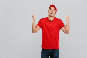 Naklejka premium Young delivery man wearing uniform screaming while making winner gesture