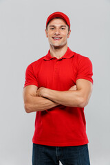 Young delivery man smiling while posing with arms crossed