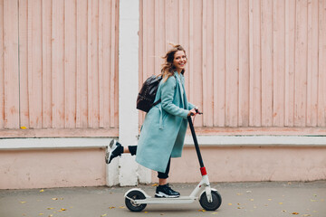 Young woman with electric scooter at the city. - obrazy, fototapety, plakaty