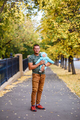 Fototapeta premium muscular man in brown pants and a newborn baby in her arms in the fall