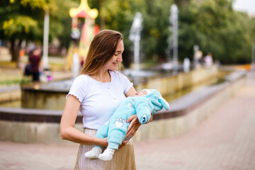 a woman holds a baby in a warm jumpsuit on the street.