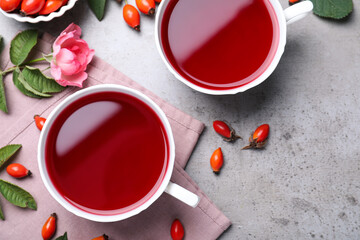 Obraz na płótnie Canvas Fresh rose hip tea and berries on grey table, flat lay
