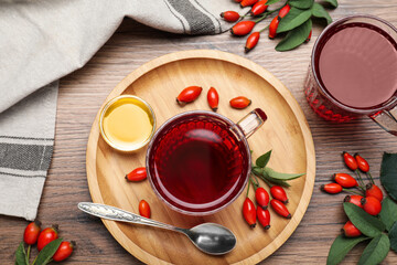 Fresh rose hip tea, honey and berries on wooden table, flat lay
