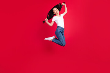 Full size profile side photo of young cheerful asian girl happy positive smile jump up active isolated over red color background