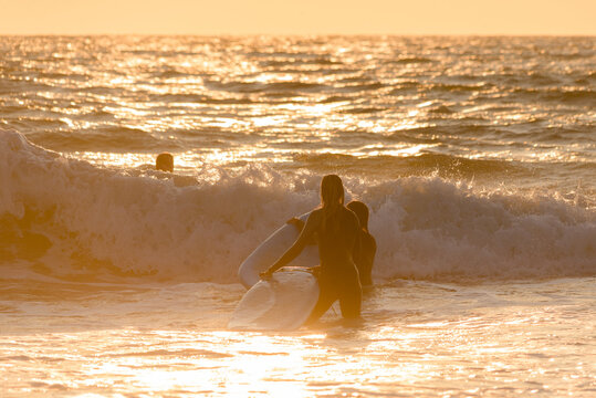 two friends entering the water for a beautiful sunset surf session.