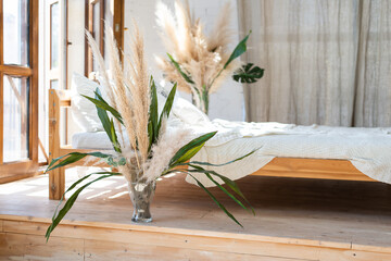 Light bedroom in Scandinavian style. Pampas grass in glass vases