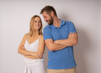 Portrait of caucasian couple man and woman in casual clothing smiling at each other standing with arms crossed isolated over white background