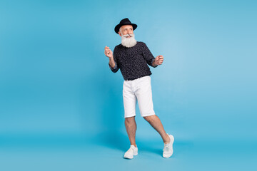 Full body photo of dreamy happy positive old man look empty space dance enjoy isolated on blue color background