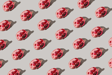 Creative pattern made of fresh slices of pomegranate on pastel grey background with sunlit. Minimal style. Top view. Flat lay .