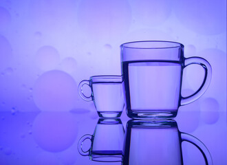transparent glass with water and oil drops on colored background