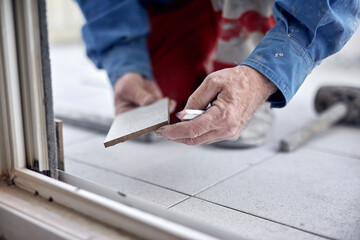 Fototapeta na wymiar Professional ceramics tile man worker placing new tiles on the floor and wall.