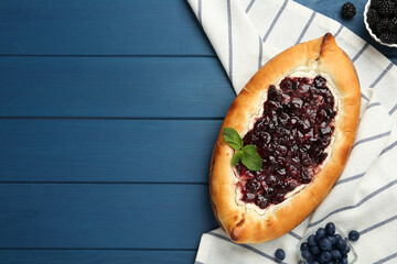 Delicious sweet cottage cheese pastry with cherry jam on blue wooden table, flat lay. Space for text