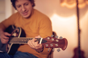 Male musician playing acoustic guitar on the amplifier in retro vintage room.