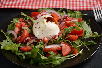 Salad with Tomatoes and Burrata cheese with basil and olive oil on dark background. Traditional Italian dish burrata cheese. Burrata served with tomatoes and arugula