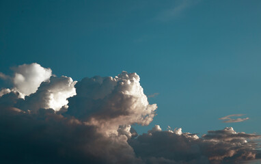 A bright blue sky with huge clouds forming and moving in the wind.