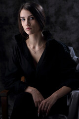 Portrait of a beautiful girl in a black men's shirt on a dark background