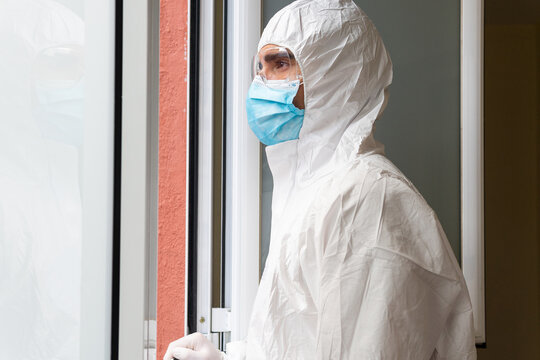 Doctor in PPE suit breathing against window in clinic - Powered by Adobe