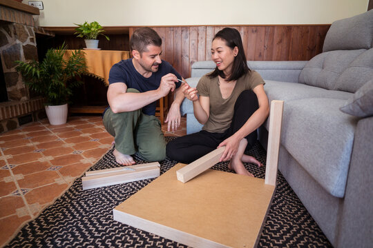 Multiracial couple assembling table on rug in house