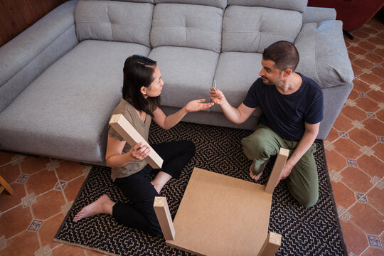 Multiracial couple assembling table on rug in house