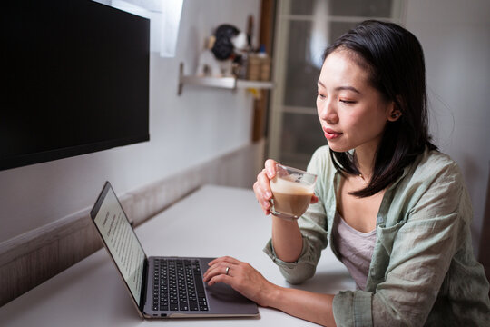 Asian writer with laptop and coffee at home