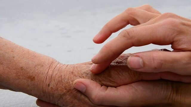 A young hand touches an old hand. Thanks to the parents. Seniors concept. Old hands of the grandmother. Young and old hands in place. Support and care. Support. Kindness and mercy