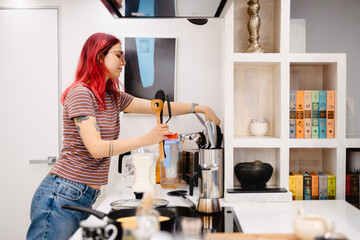 Young white woman with red hair cooking in kitchen at home