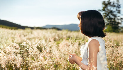 Fototapeta na wymiar Asian girl in white dress in field at sunset