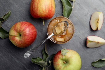 Tasty apple jam in glass jar and fresh fruits on grey table, flat lay