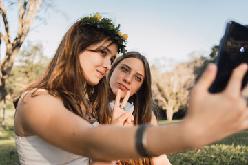 Girlfriends showing peace gesture while taking selfie on smartphone