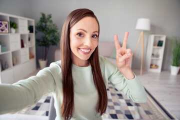 Self-portrait of attractive cheerful woman staying safe showing v-sign good mood free time at home indoors