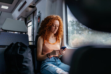 Passenger chatting on smartphone against window on train