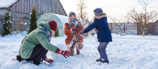 Winter games with snow.Happy family playing in the yard of the house in social distance, lockdown.Digital detox, slowdown, real moments, slow life,staycation