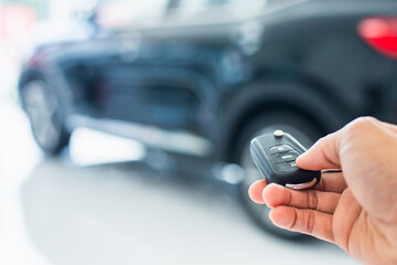 Salesman is carrying the car keys delivered to the customer at the showroom with a low interest offer. Special promotion, auto business, car sale, deal, gesture and people concept.