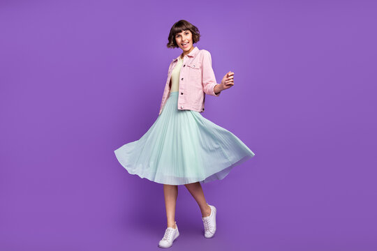 Full length photo of young pretty cheerful amazed woman wear skirt wind blow isolated on violet color background