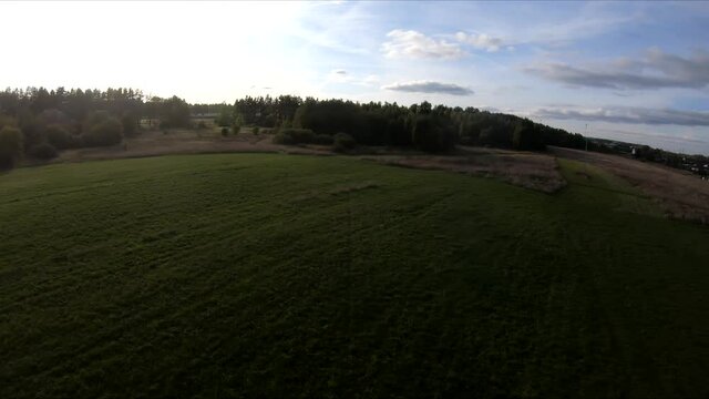 flying on an fpv drone behind a horse, a girl on a horse, in a green field, against the background of a forest, bushes, trees, blue sky, white clouds