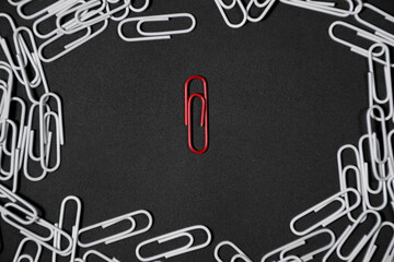 Frame made of paperclip on black background and there is a red paperclip isolated in the frame