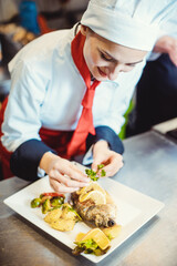 Chef cook in a fancy restaurant kitchen finishing a dish with care and diligence
