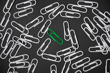Green paper clip unique idea concept on black background. Stand out of the crowd