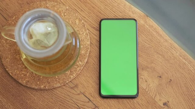 Smartphone place on table wood with green screen, Close-up the cell phone is on the brown table in the restaurant with chroma key, Green screen telephone, and top view